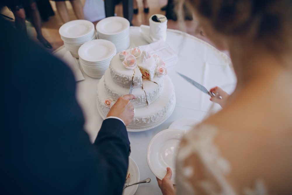 Sposi durante il taglio della torta nuziale con servizio di catering per matrimoni e tavolo elegante per il ricevimento.